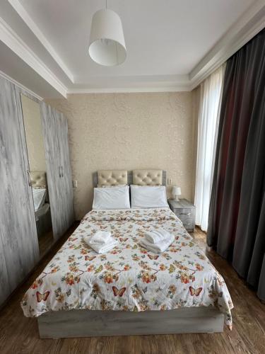 1 dormitorio con 1 cama con colcha de flores en Rustaveli Apartment 113, en Kutaisi