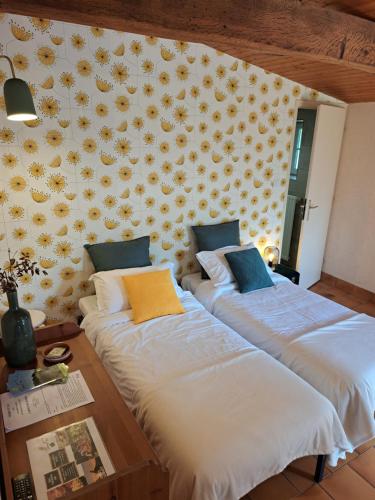 - 2 lits dans une chambre ornée de fleurs sur le mur dans l'établissement Terre et Eau La chambre d'hôtes du jardinier Sèvremont, à Sevremont