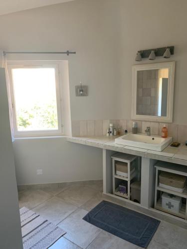 une salle de bain blanche avec un lavabo et une fenêtre dans l'établissement Maison de charme à Lourmarin, à Lourmarin