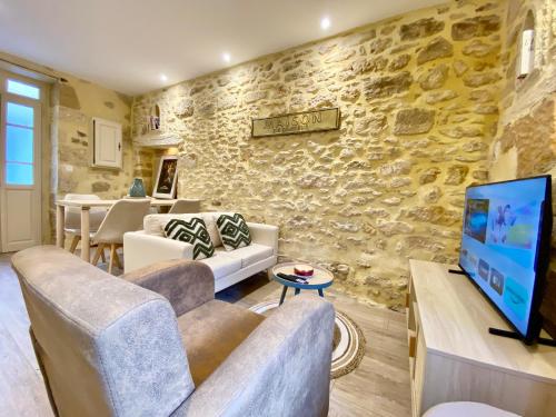 a living room with a stone wall and a tv at Montignac-Lascaux - Les Pierres De Lascaux in Montignac