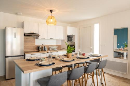 a kitchen with a large wooden table with chairs at Le Noyer - moderne - spacieux - parking in Montaigu-Vendée