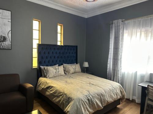 a bedroom with a bed with a blue headboard and a window at the curve apartments unit 26 in Johannesburg
