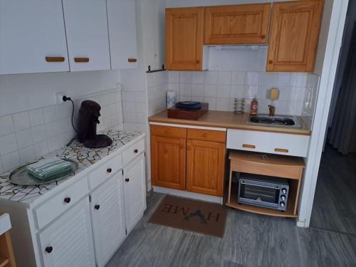 une petite cuisine avec des armoires blanches et un micro-ondes dans l'établissement L'escale à deux pas de la mer, à Bretignolles-sur-Mer