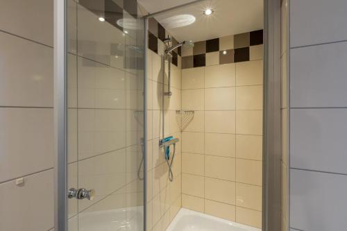 a shower with a glass door next to a tub at Vakantiewoning in centrum Zoutelande, bij het strand in Zoutelande