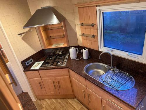 a kitchen with a sink and a stove and a window at Atlas 2 Bedroom Caravan, Glasgow in Uddingston