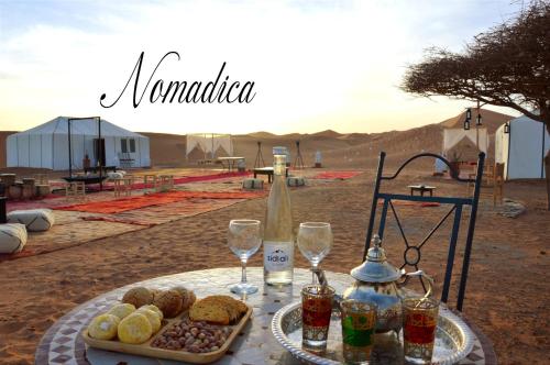 a table with food and wine glasses in the desert at Nomadica Luxury Camp in Merzouga