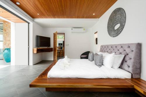 een slaapkamer met een groot wit bed en een televisie bij 塔羅别墅-直通海滩的三卧海滨别墅 in Koh Samui 
