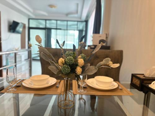 un tavolo con piatti e un vaso con fiori sopra di Service Apartment ใจกลางเมืองใกล้แหล่งท่องเที่ยว119ทับ1ถนนปงสนุก a Lampang
