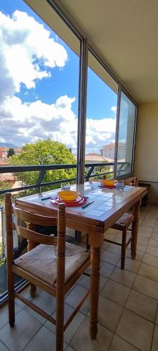 une table en bois avec des chaises et une vue sur un pont dans l'établissement La Croisette, parking, proche plage, à La Seyne-sur-Mer