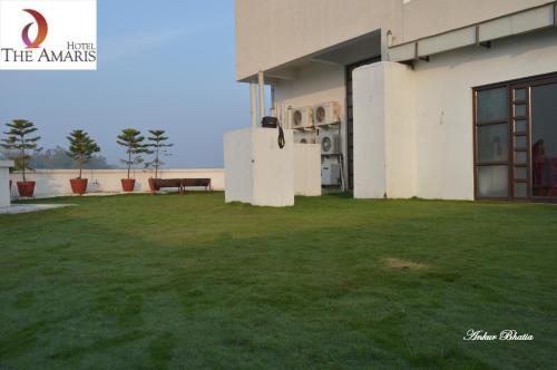 a building with a large yard with a green lawn at Hotel The Amaris in Rishīkesh