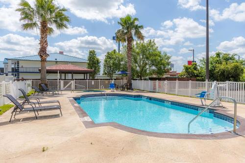 a swimming pool with chairs and palm trees at Microtel Inn & Suites by Wyndham Kingsland Naval Base I-95 in Kingsland
