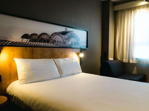 una camera d'albergo con letto e sedia di Ibis Valladolid a Valladolid