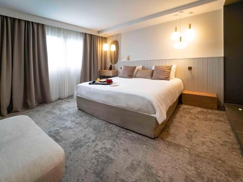 a hotel room with a large bed and a window at Mercure Bordeaux Lac in Bordeaux