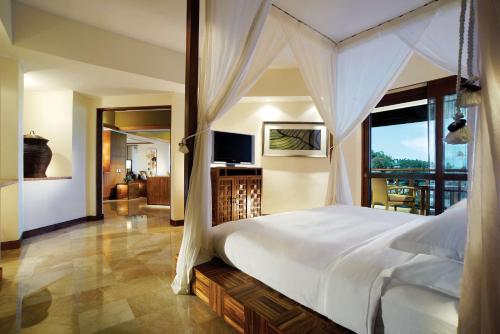 een slaapkamer met een groot wit bed en een televisie bij Grand Hyatt Bali in Nusa Dua