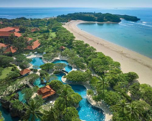 an aerial view of a beach with blue water and trees at Grand Hyatt Bali in Nusa Dua