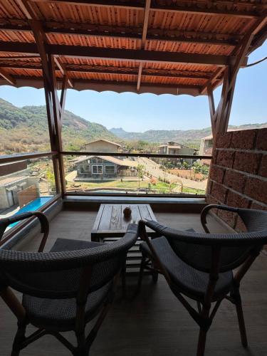 a balcony with two chairs and a table and a view at Mastiff Grand La Villae in Lonavala