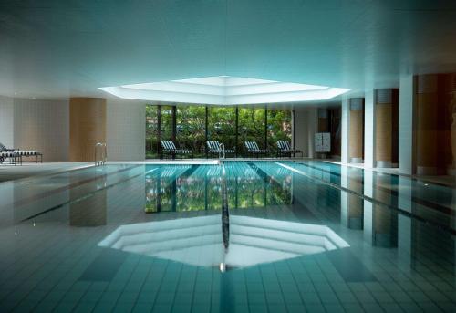 a large swimming pool with chairs in a building at Grand Hyatt Fukuoka in Fukuoka