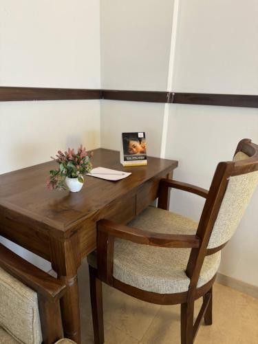 a wooden table with two chairs and a vase of flowers at Mastiff Grand La Villae in Lonavala