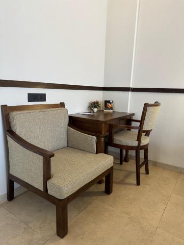 two chairs and a table in a room with a desk at Mastiff Grand La Villae in Lonavala