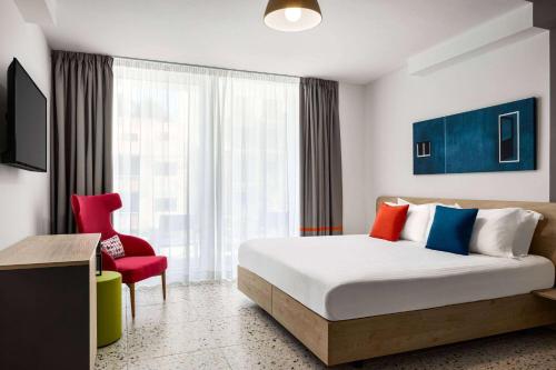 a hotel room with a bed and a red chair at Quadro Hotel, Trademark Collection by Wyndham in St Julian's