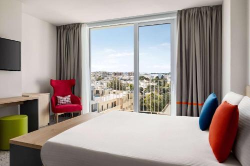 a hotel room with a bed and a large window at Quadro Hotel, Trademark Collection by Wyndham in St Julian's