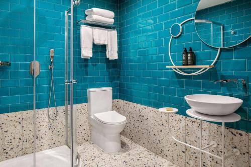 a blue bathroom with a toilet and a shower at Quadro Hotel, Trademark Collection by Wyndham in St Julian's