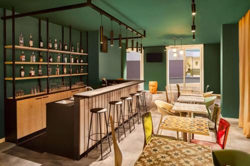a restaurant with green walls and a bar with chairs at Quadro Hotel, Trademark Collection by Wyndham in St Julian's