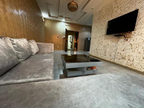 a living room with a couch and a tv on a wall at Prestige House in Ouagadougou