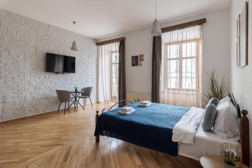 ein Schlafzimmer mit einem Bett mit einer blauen Decke in der Unterkunft Rynok Square apartment with balcony in Lwiw