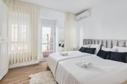a white bedroom with a large bed and a window at Modern Living in Kings Courtyard in Jerusalem