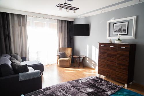 a bedroom with a living room with a couch and a tv at Apartament Rynek 10 in Ostrowiec Świętokrzyski