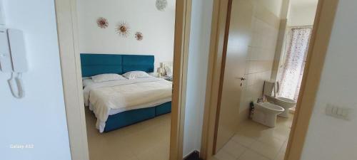 a bedroom with a bed with a blue headboard and a bathroom at Grace in Vlorë