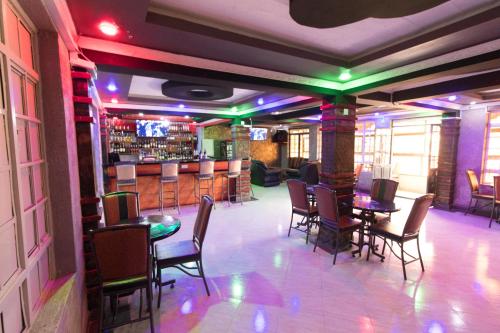 um restaurante com mesas e cadeiras e um bar em Africa One Hotel em Naro Moru