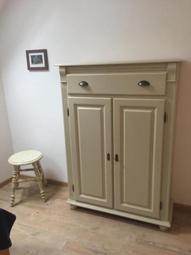 a white cabinet in a room with a stool at Unter Eichen in Uplengen