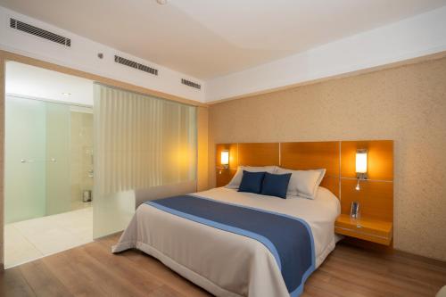 デニズリにあるAnemon Grand Denizli Otelのベッドルーム(青い枕の大型ベッド1台付)