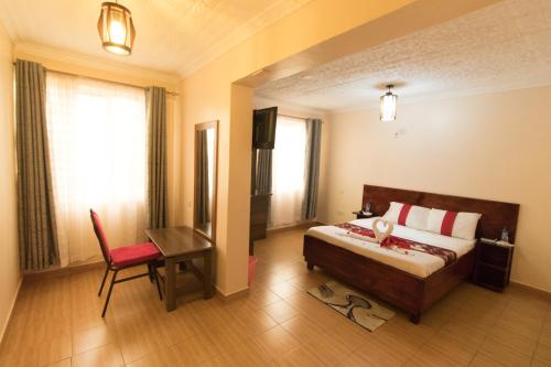 um quarto com uma cama, uma mesa e uma cadeira em Africa One Hotel em Naro Moru