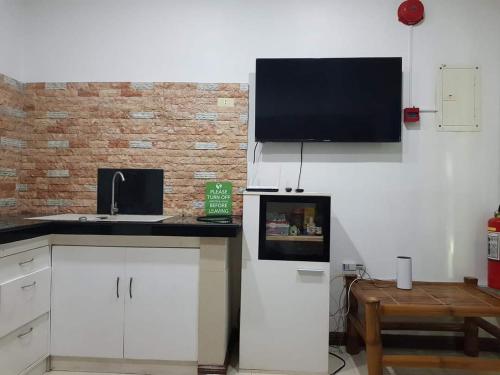 a kitchen with a sink and a tv on the wall at Homaja Roomrental in Panglao