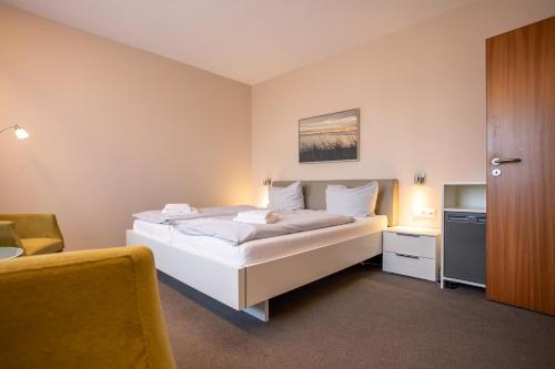 a bedroom with a large white bed and a chair at Lieblingsplatz Seedeich in Grömitz