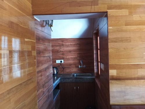 a bathroom with a sink and wooden walls at Khushi Cottage in Mukteswar