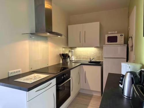 une cuisine avec des armoires blanches et un comptoir noir dans l'établissement Les Terrasses de la Mer, à Dinard