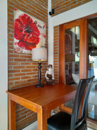 a table with a lamp and a painting on a brick wall at As I Am Ubud Retreat in Ubud