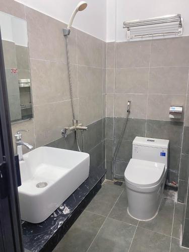 a bathroom with a white toilet and a sink at Nhà Nghỉ Ánh Ngọc in Hue