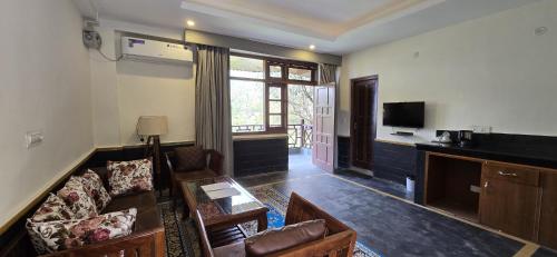 a living room with a couch and a tv at Blossoms Village Resort in Dharamshala