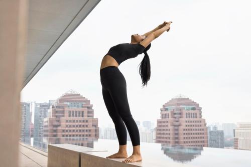 a woman doing a yoga pose on the ledge of a building at COMO Metropolitan Singapore in Singapore