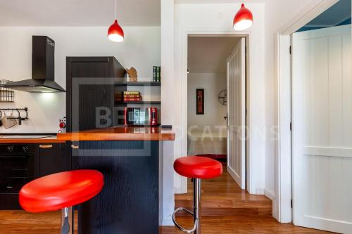 une cuisine avec tabourets rouges à un comptoir dans l'établissement Appartamento Baia Azzurra - BeLocations, à Capitana