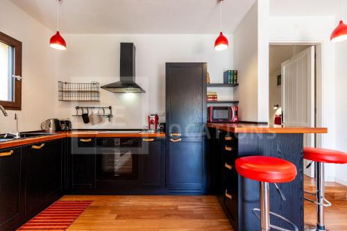 une cuisine avec des placards noirs et des tabourets de bar rouges dans l'établissement Appartamento Baia Azzurra - BeLocations, à Capitana