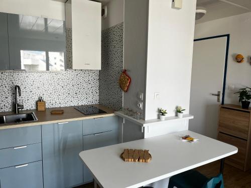 a kitchen with white cabinets and a white table at BELLE VUE OCEAN, 2 CHAMBRES, terrasse 30m2, parking privatif et piscine en été in Lacanau-Océan