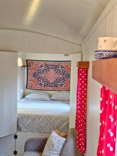 Dormitorio pequeño con cama y alfombra en la pared en pipowagen met prive Hot tub, en Lanaken