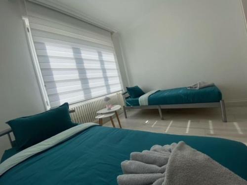a bedroom with a blue bed and a window at Appartement des 3 pays. 2 mn de Bâle+ Free parking in Saint-Louis