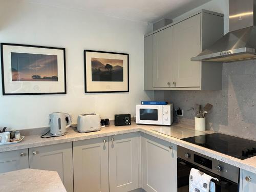 a kitchen with white cabinets and a microwave at Thisledo Holiday Cottage SKIPTON Early check in available on request in Skipton